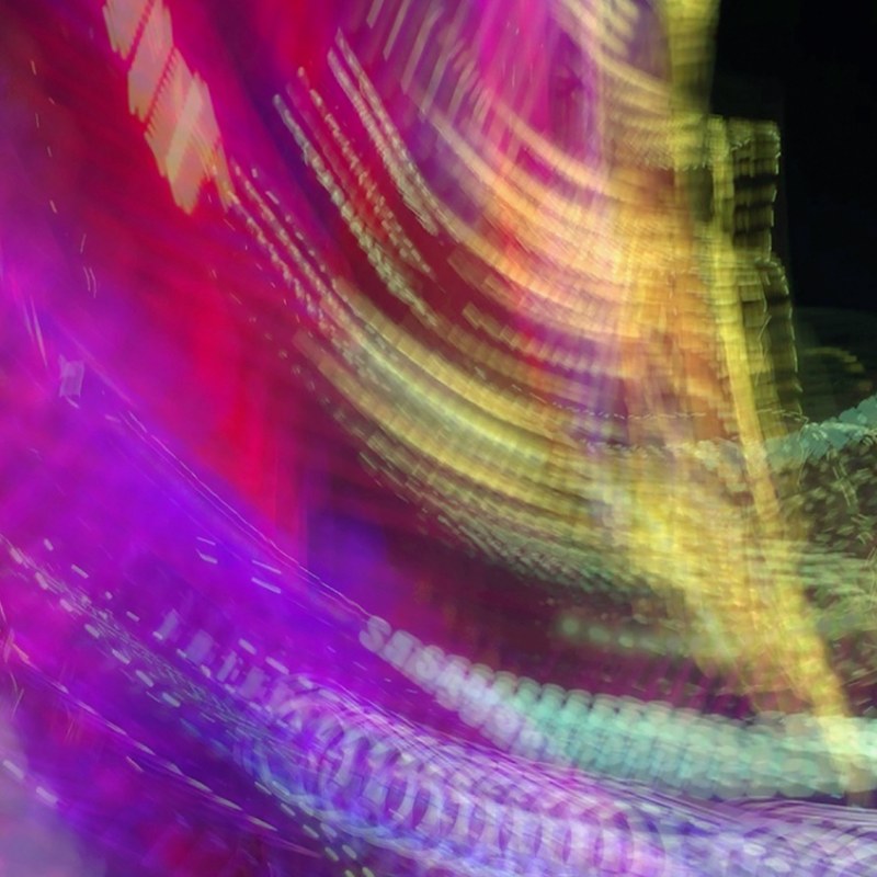 A magnified detail of Into the Dance: magenta and yellow light curved into sweeping arcs of fine dotted strands